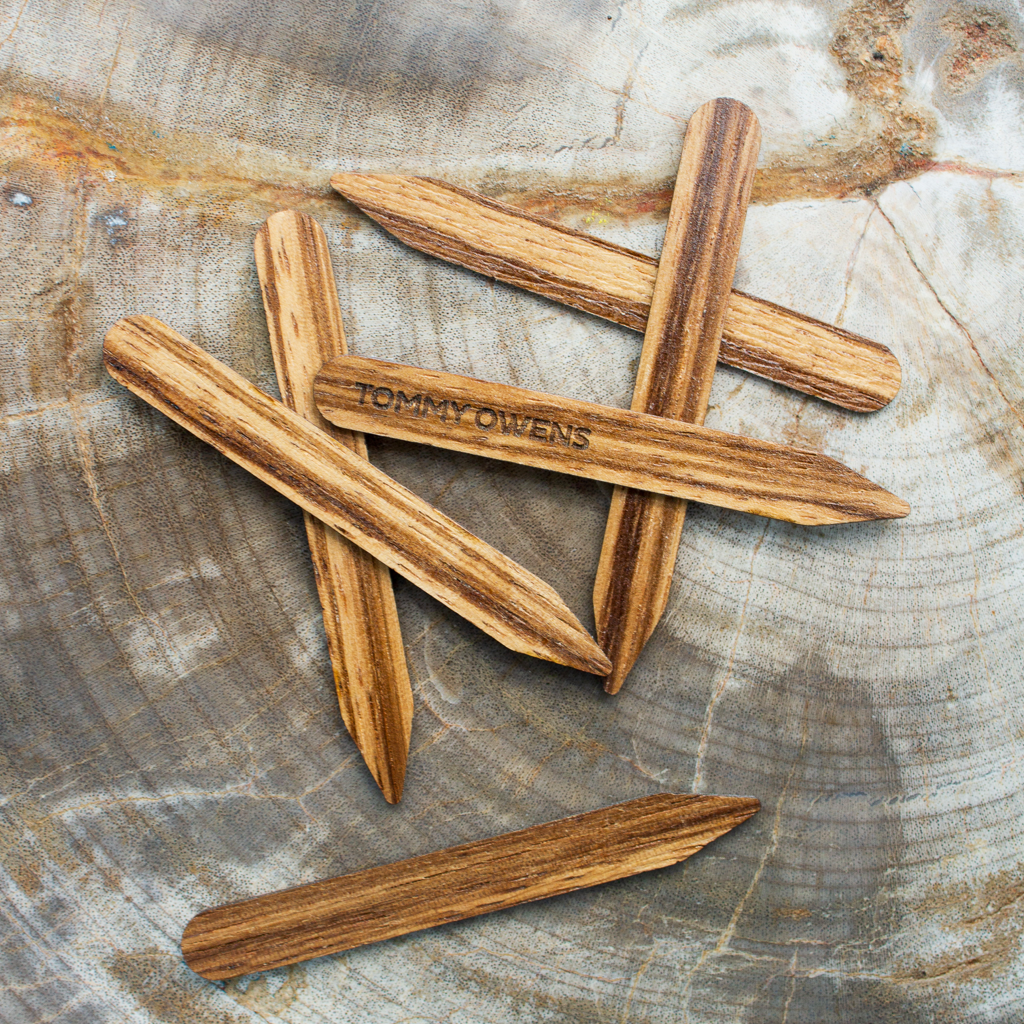 Zebrawood collar stays scattered on a black and white surface, highlighting their striking grain pattern and contrast.