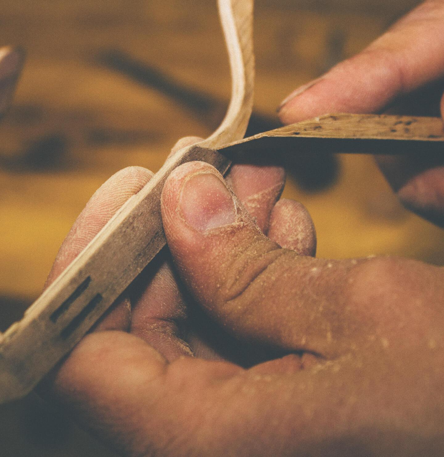 Hand-finishing a Delray frame in walnut and maple wood to create smooth, refined edges in the Tommy Owens workshop