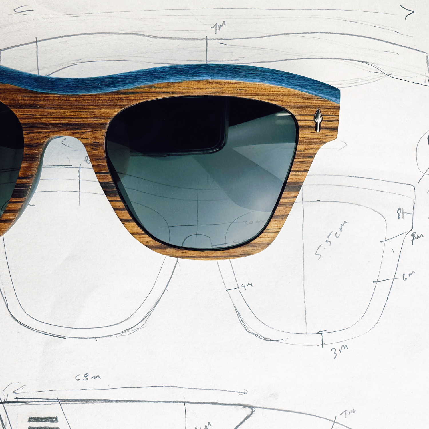 Michaela zebrawood and turquoise maple sunglasses over early frame sketches, showing design to product