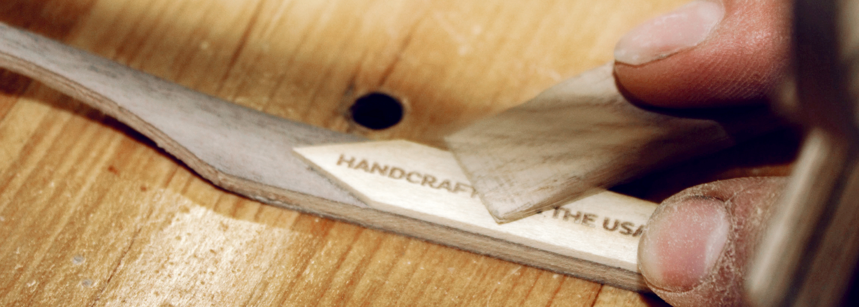 Hand sanding a walnut and maple wood frame during the handcrafted eyewear process in the Tommy Owens workshop