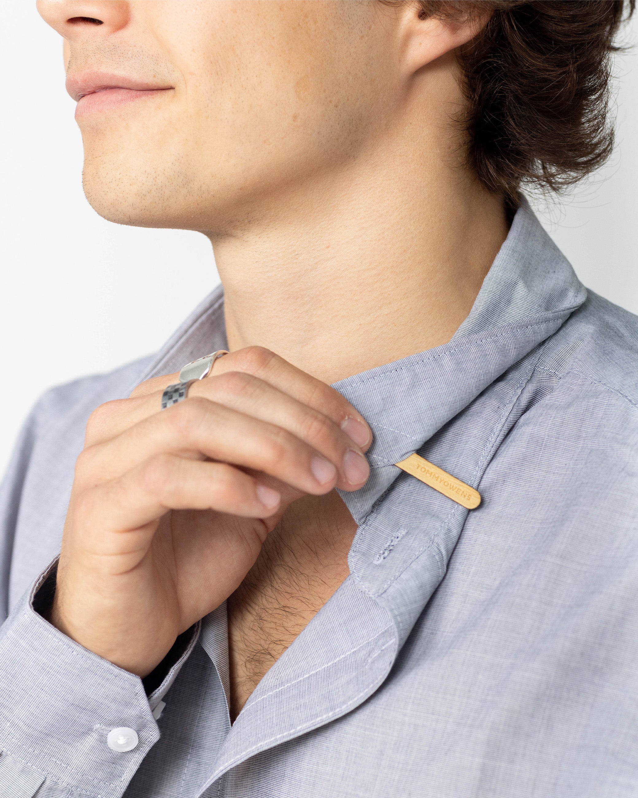 Man inserting a rosewood collar stay into his dress shirt, demonstrating the proper way to achieve a crisp and polished collar.