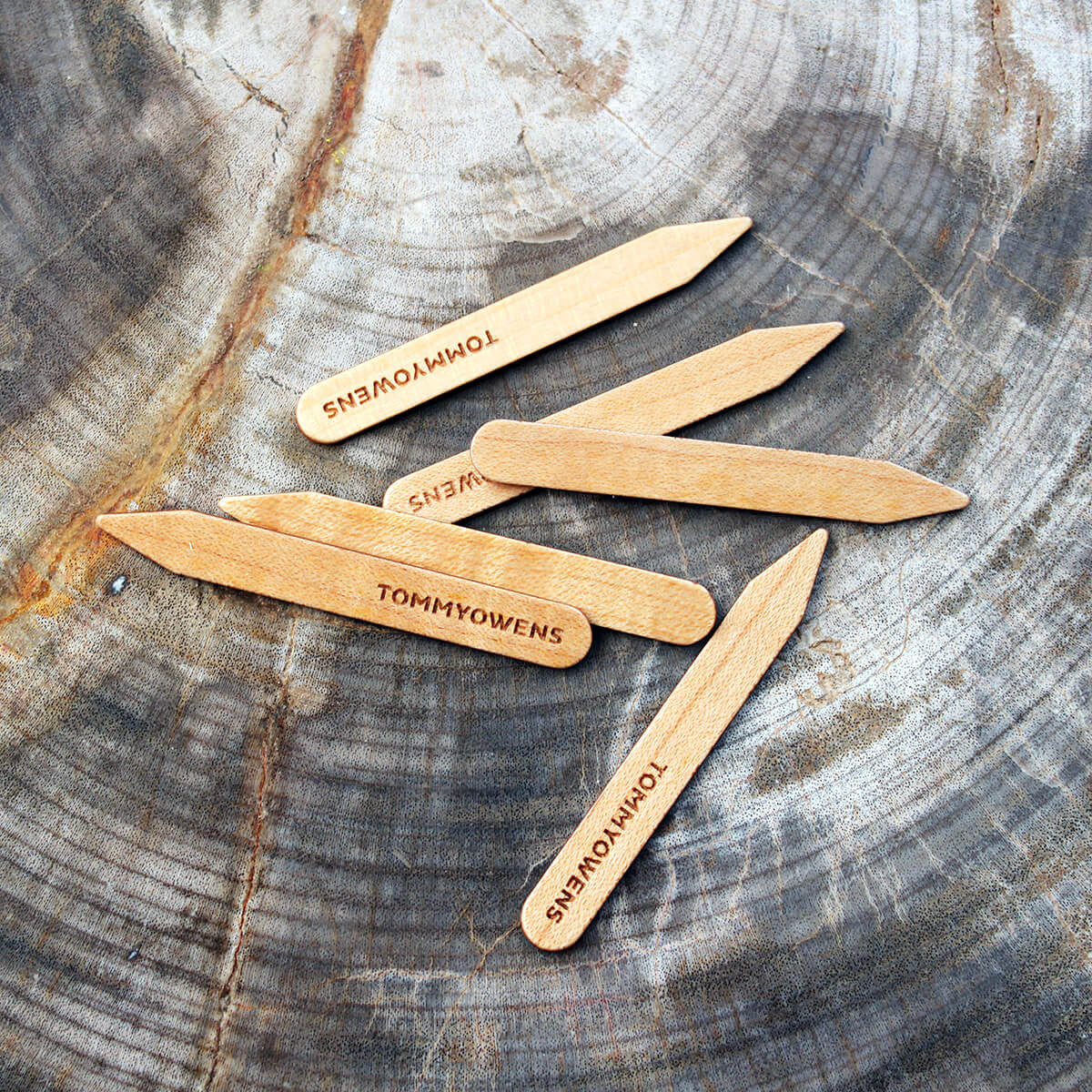 Curly maple collar stays arranged in a pattern, highlighting their mesmerizing figured grain and handcrafted quality.