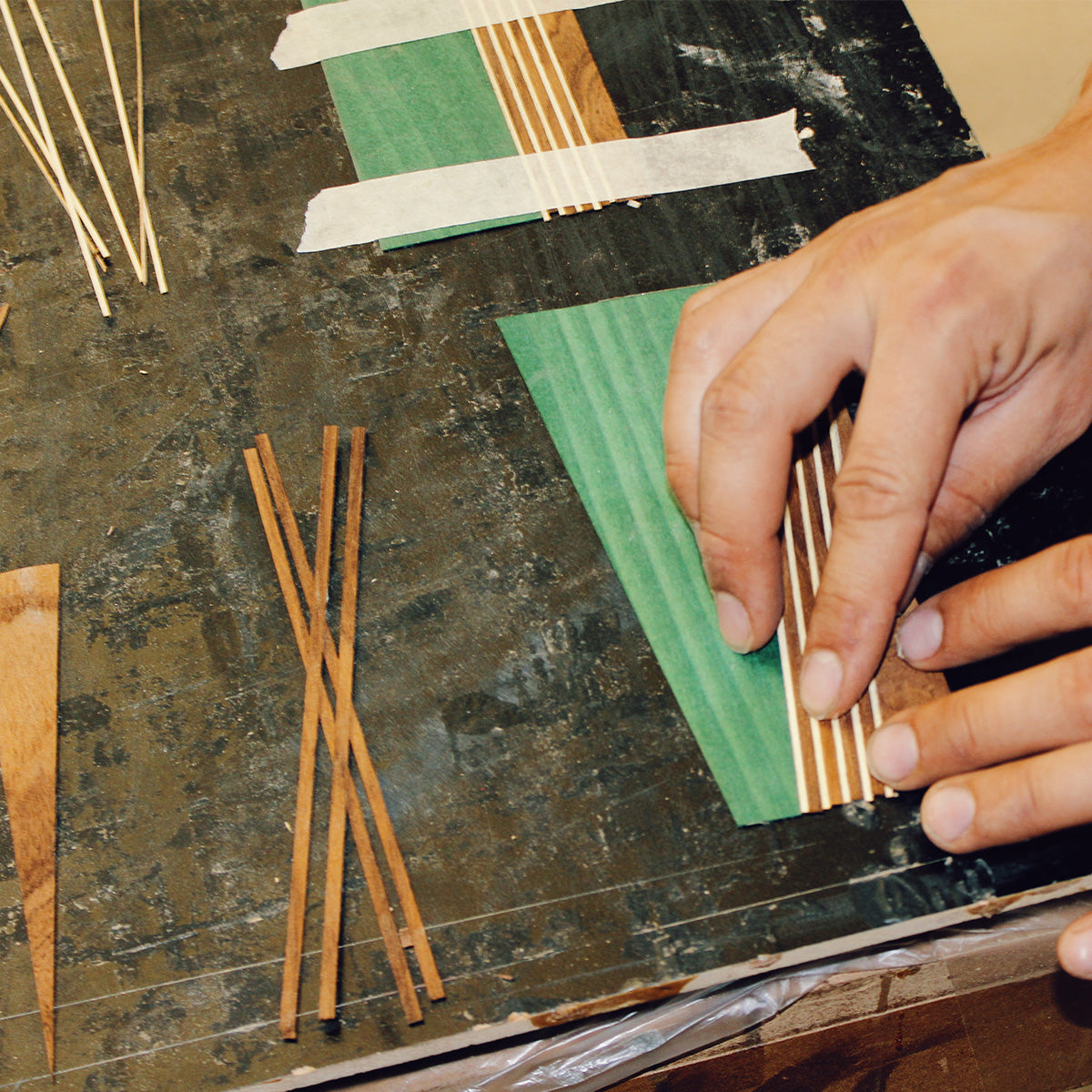 Hand assembling green maple, teak, and ash strips to create the Tommy Owens Maritime signature frame pattern